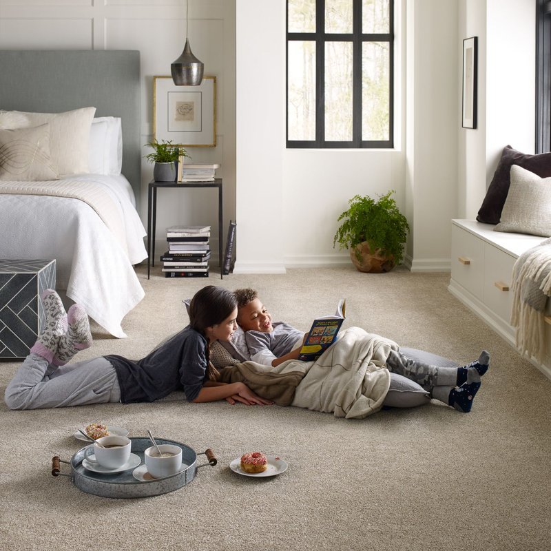 two kids laying on carpet reading book in bedroom
